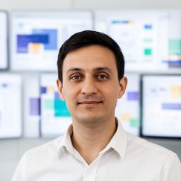 Portrait of Azouz Solez in a bright workspace beside multiple monitor screens